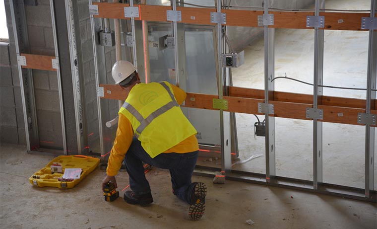 Man on construction site using Spectra Precision hardware to check wall alignment