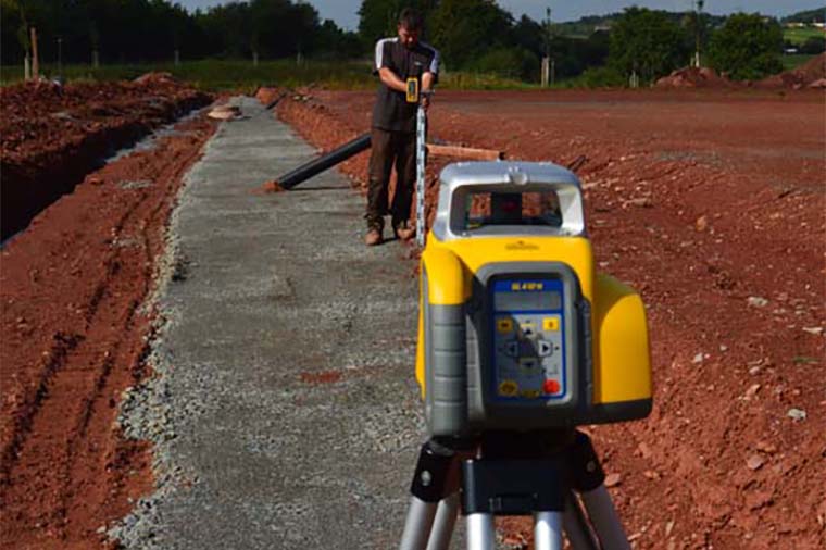 Man using Spectra Precision grade laser to survey path