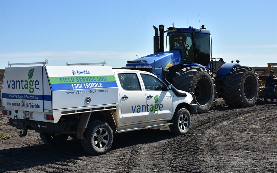 Vantage NEA branded vehicle in front of tractor on farm
